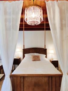 una camera da letto con un letto grande con un lampadario di La Chaumière aux hortensias a Saint-Jouin-Bruneval Altre 28 foto
