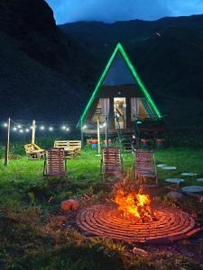a fire pit with chairs and a gazebo at night at Gudika • გუდიკა in Sno