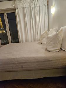 un letto con cuscini bianchi e una finestra di Pépite Tour Eiffel a Parigi