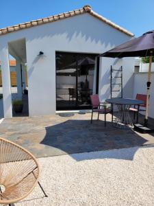 a patio with a table and chairs and an umbrella at Air marin in La Bernerie-en-Retz