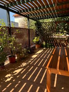 un banco de madera sentado bajo una pérgola de madera en Artemis Airport Stay, en Artemida