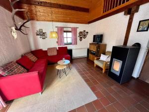 a living room with a red couch and a fireplace at Waldferienhaus 98 im bayerischen Waldferiendorf I 3 Schlafzimmer I Lagerfeuerplatz in Regen
