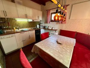 a kitchen with a table and red chairs and a kitchen with a sink at Waldferienhaus 98 im bayerischen Waldferiendorf I 3 Schlafzimmer I Lagerfeuerplatz in Regen