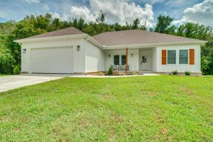 a white house with a garage in a yard at Flippin Vacation Rental Walk to White River! in Flippin