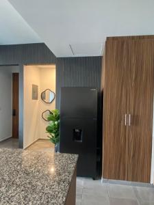 a kitchen with a black refrigerator and wooden cabinets at Departamento con vista al mar en Cabo Marino in Conchal