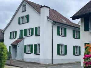 a white and green house with green shutters at Charmante Wohnung im alten Dorfkern in Winterthur