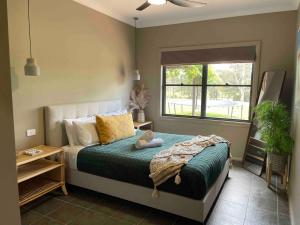 a bedroom with a bed with a green comforter and a window at Live Like Kings Entire Property Ironstone Estate in Lovedale +159 photos