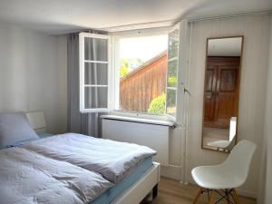 a bedroom with a bed and a window and a chair at Charmante Wohnung im alten Dorfkern in Winterthur