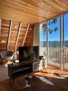 a living room with a tv and a large window at Cabana Snowflake Urubici in Urubici
