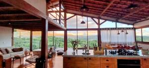 a living room with a kitchen and a large window at Casa Miralago in Santana do Riacho +82 photos