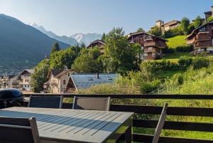 drewniany stół i krzesła na balkonie z widokiem na góry w obiekcie Chalet La Cordée, 160m2, 4 chambres, sauna w mieście Saint-Gervais-les-Bains