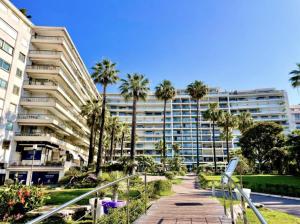 a large apartment building with palm trees and a walkway at Luxury Romantic Cannes 45 Croisette Two Bedrooms in Cannes