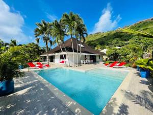 a villa with a swimming pool and palm trees at Villa Moana Reva in Bora Bora