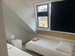 a bedroom with two beds and a large window at Torensduin aan zee in Egmond aan Zee
