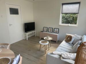 a living room with a couch and a tv at Torensduin aan zee in Egmond aan Zee