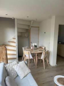 a living room with a table and chairs and stairs at Torensduin aan zee in Egmond aan Zee