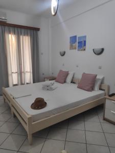 un grande letto in una stanza con un cappello sopra di Villa Dora Studios a Mpatsi (Batsi)