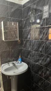 a bathroom with a sink and a black tiled wall at Chalé da Montanha in Resende