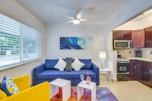 Una sala de estar con un sofá azul y una cocina. en 2 Mi to Ocean Dog-Friendly Hallandale Beach Condo, en Hallandale Beach