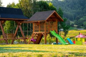 a playground with a wooden play structure and a slide at Modrzewiowa Ostoja in Kluszkowce