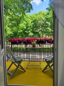 a balcony with two chairs and a table with flowers at Apartamentai Upės Namai in Šilutė