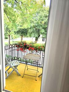 a balcony with two chairs and a table with red flowers at Apartamentai Upės Namai in Šilutė
