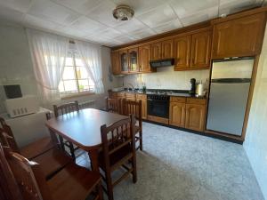 a kitchen with wooden cabinets and a table and a refrigerator at Casa - Chalet en Barizo - Malpica de Bergantiños in A Coruña
