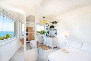 a bedroom with a bed and a kitchen with a window at Suite The Mana Vista Mare in Centro - Casamicciola Terme in Ischia