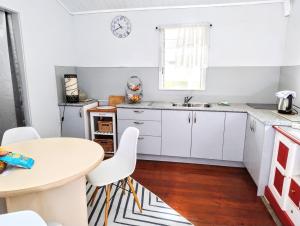 a kitchen with white cabinets and a table at Classic Queenslander Suite in Townsville