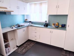a kitchen with white cabinets and a sink at Classic Queenslander Suite in Townsville