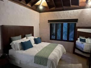 a bedroom with a large bed with blue pillows at Villa Los Tamarindos in San Juan del Sur