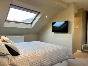 a bedroom with a bed with a television on the wall at Kirkton Rest in Cardross