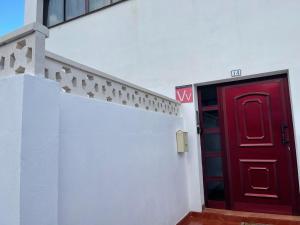 eine rote Tür an der Seite eines weißen Gebäudes in der Unterkunft Estudio con terraza in La Caleta