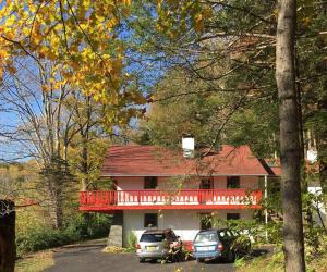 a house with a red deck and cars parked in front at Catskill Cabin Cool Apartment 2nd Fl in Shandaken