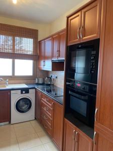 a kitchen with a washer and dryer and a microwave at Seascape apartment in Larnaca