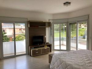 una camera con letto, TV e porte scorrevoli in vetro di Lagoa da Conceição Residence a Florianópolis