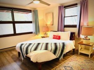 a bedroom with a large bed and two windows at Catskill Cabin Chill Apartment 1st Fl in Shandaken
