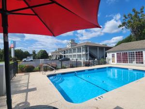 a pool with a red umbrella next to a house at SureStay Plus Hotel by Best Western Asheboro in Asheboro
