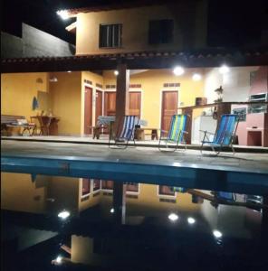 Eine Gruppe von Stühlen steht neben einem Schwimmbecken in der Unterkunft Chalé Vitória 1- Rancho dos 7 in Arapeí