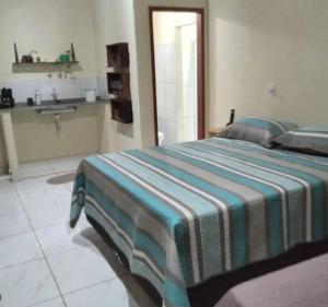 ein Schlafzimmer mit einem Bett mit gestreifter Decke in der Unterkunft Chalé Vitória 1- Rancho dos 7 in Arapeí + 25 Fotos