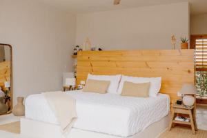 a bedroom with a white bed with a wooden headboard at CasaBlancoMadera in Todos Santos
