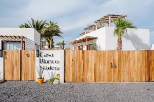 a wooden fence with a sign in front of a house at CasaBlancoMadera in Todos Santos +52 photos
