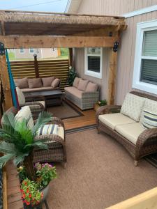 a patio with wicker chairs and a pergola at LUXURY ROSE COTTAGE ,ABOITEAU BEACH,CAP PELE in Cap-Pele