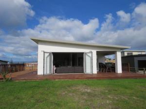 a white house with a deck with a patio at Cleggs Batch in Karikari Peninsula