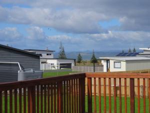 a wooden deck with a yard with houses and buildings at Cleggs Batch in Karikari Peninsula