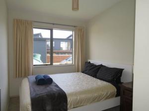 a bedroom with a bed and a large window at Cleggs Batch in Karikari Peninsula