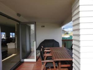 a wooden table and chairs on a porch with a patio at Cleggs Batch in Karikari Peninsula