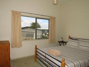 a bedroom with a bed and a large window at Cleggs Batch in Karikari Peninsula
