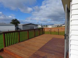 a porch with a wooden deck with a fence at Cleggs Batch in Karikari Peninsula