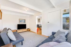 a living room with a couch and a tv at 52 Ballingalla Street, Narooma in Narooma